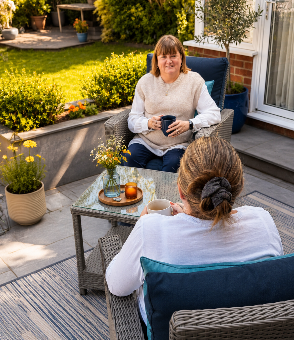 Counsellor and client talking over coffee in a peaceful garden setting